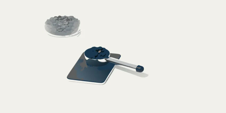 A bean scale scoop holding coffee beans on a digital scale.